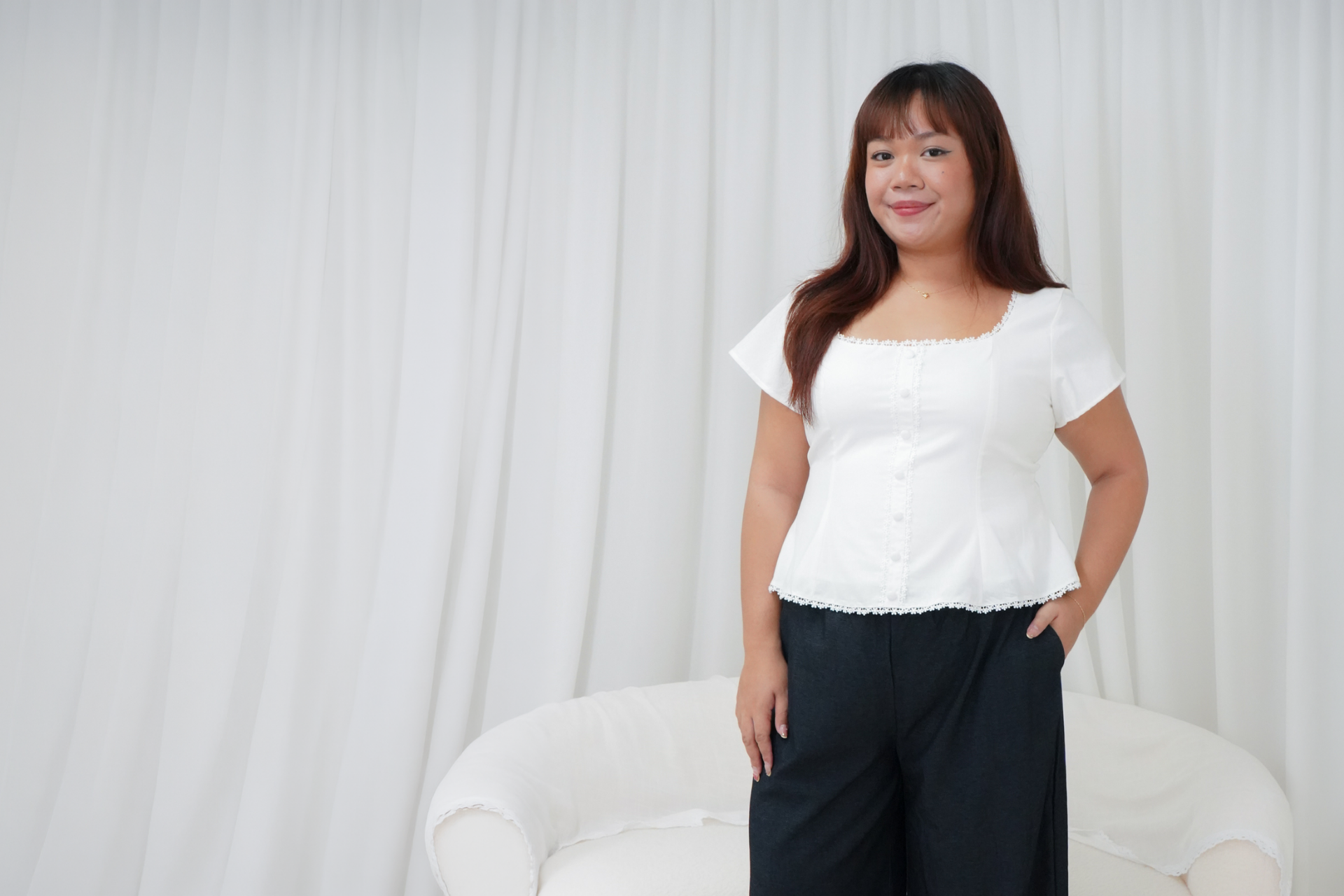 Model wearing a white blouse and black trousers from The Fleur Label